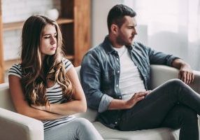 a divorcing couple sitting unhappily on a couch